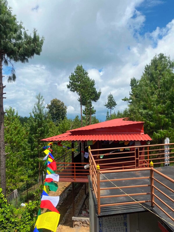 A red-roofed structure with a wooden railing, surrounded by greenery and trees.