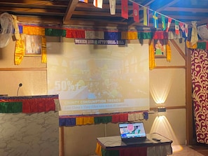 Pantalla de presentación con un cartel de 50% de descuento, una laptop sobre un soporte y banderas de colores en el techo.
