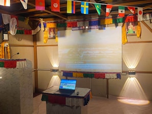 Un área de presentaciones con una computadora portátil, una pantalla de proyector mostrando una diapositiva sobre China y un banderín con banderas.