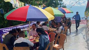 Un groupe de personnes déjeunant ou dînant sous des parasols colorés lors d’un événement en plein air.