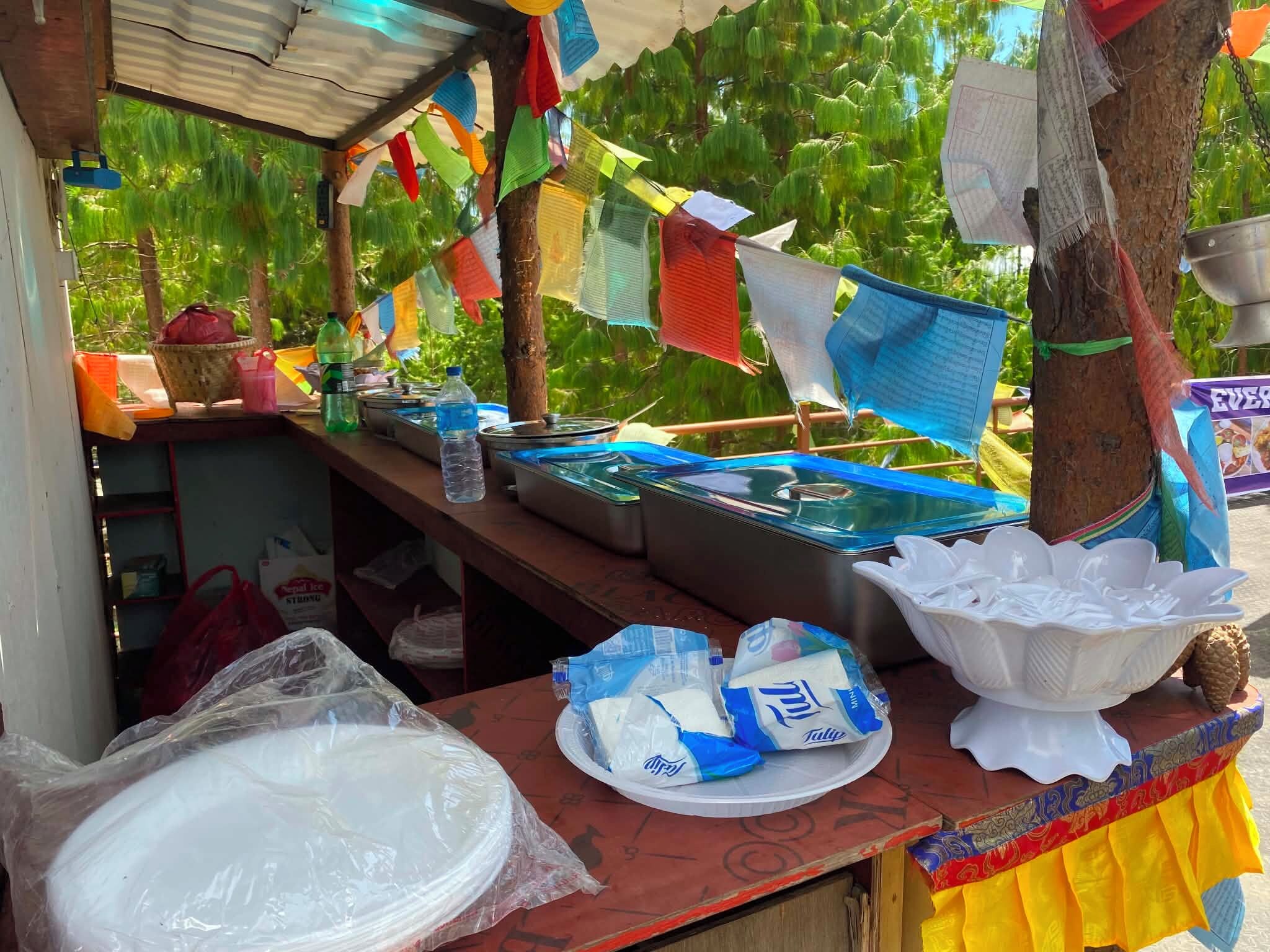 Un étal avec une table où sont exposés divers articles, notamment des produits emballés, un bol en plastique et un récipient en métal.