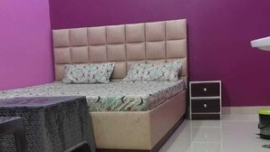A bedroom with a bed, a desk, a chair, and a wall-mounted air conditioner. - Hotel Aparna Palace  (Basti)