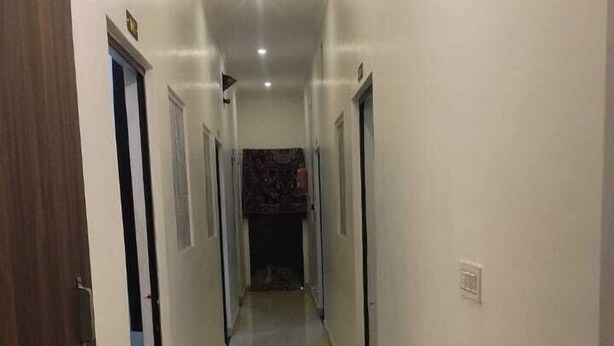 A long, narrow hallway with white walls and a tiled floor. - Hotel Aparna Palace  (Basti)