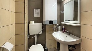 A small, modern bathroom with a toilet, sink, and hand dryer. - Meli Studio 304 – Comfort & Functionality for up to 4 Guest (Paralia)