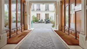 A corridor with a tiled floor leading to a courtyard with a bicycle and a scooter. - Sublime apartment in the center of Paris (Paris)