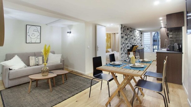 Ein modernes Wohnzimmer mit einer Couch, einem Couchtisch und einem Essbereich mit Stühlen und einem Tisch für zwei Personen.