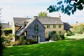 A two-story house with a sloped roof, a front porch, and a well-maintained lawn. - Cotswold Country House in Charlbury (Charlbury)