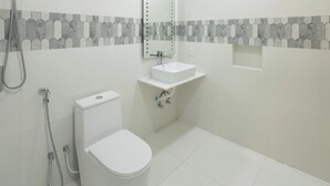 Un baño moderno con inodoro, lavamanos y ducha.
