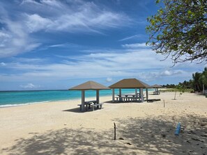 A beach with two gazebos, a clear blue sky, and a calm sea. - Gorgeous 7-bedroom house with AC in peaceful Shaviyani Atoll Milandhoo, Maldives (Milandhoo)