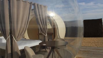Una habitación con cúpula transparente, con una cama, una mesa y sillas.