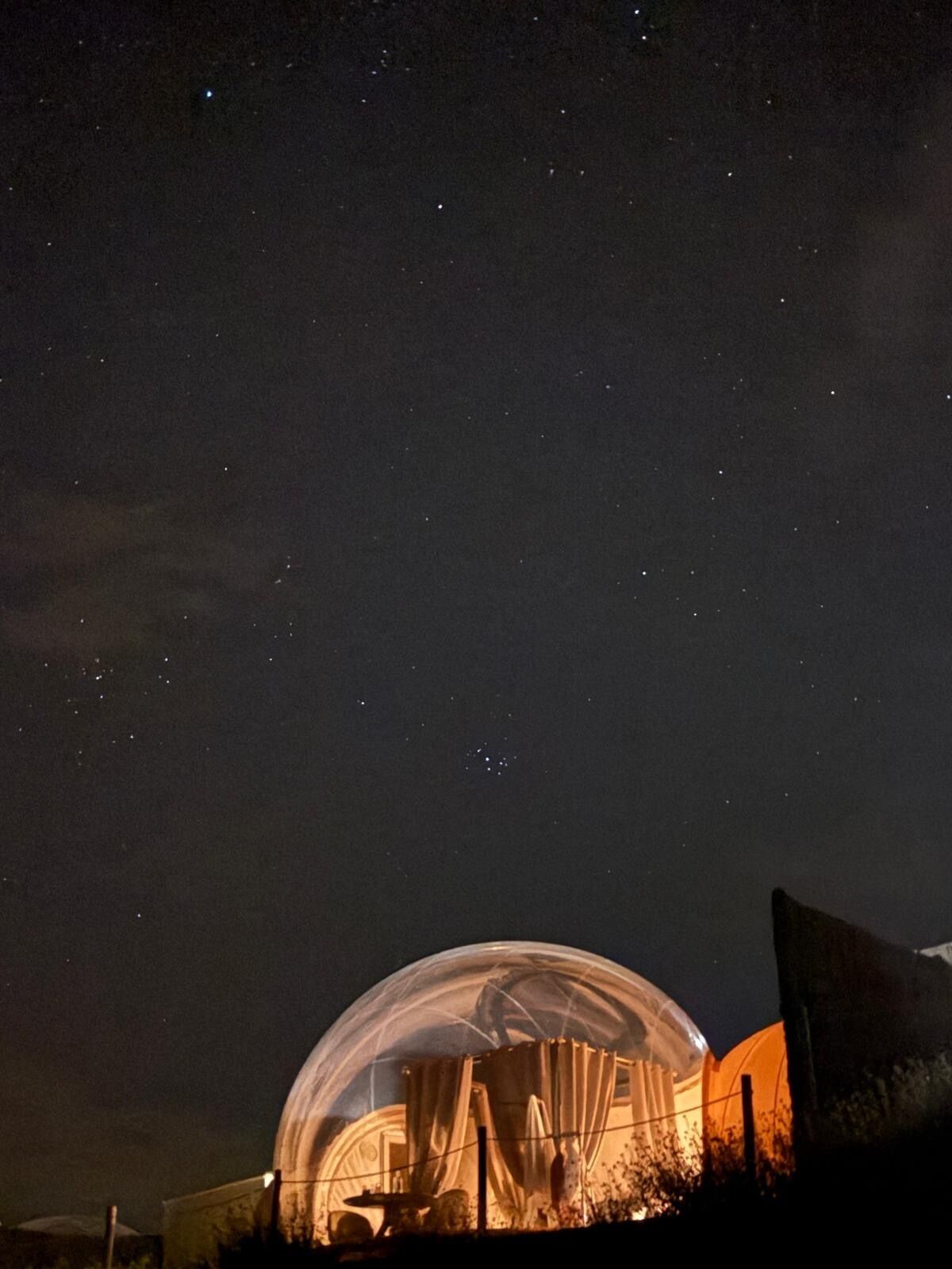 Una estructura en forma de cúpula con techo transparente, posiblemente un planetario u observatorio, bajo un cielo estrellado.
