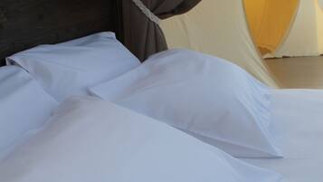A bed with white linens and a dark wooden headboard.
