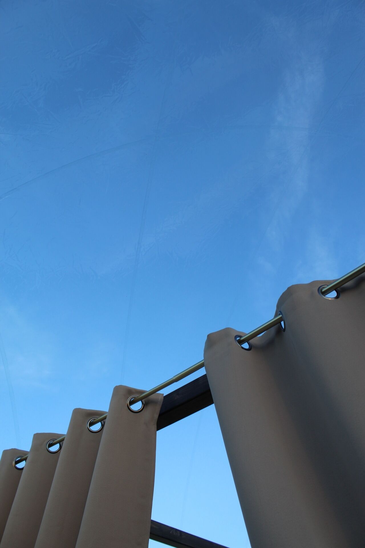 A clear blue sky with a metal structure featuring cylindrical shapes and circular rings.
