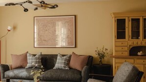 A living room with a sofa, armchair, and a patterned rug. - Luxury Stay in Heart of the Cotswolds (Cheltenham)
