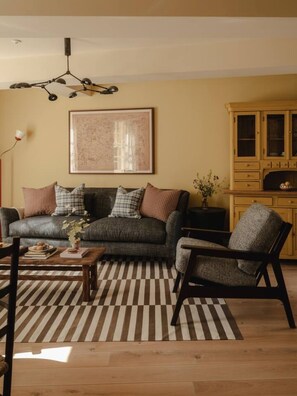 Ein Wohnzimmer mit einer Couch, einem Sessel und einem gemusterten Teppich.