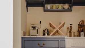 A kitchen with a built-in refrigerator, shelves with jars and bottles, and a coffee machine.