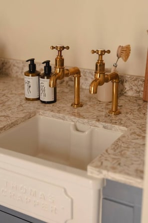 A bathroom with a white sink, two gold faucets, and two bottles of liquid soap.