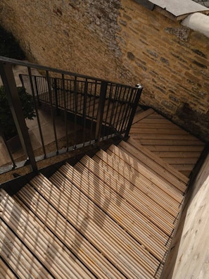 A wooden staircase with metal railings leading to a stone wall.