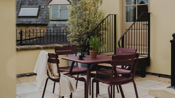 A patio with a table and chairs, a potted plant, and a staircase.