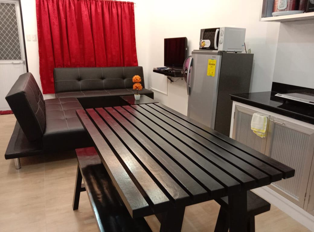 A compact living space with a sofa, a dining table, a refrigerator, and a microwave.