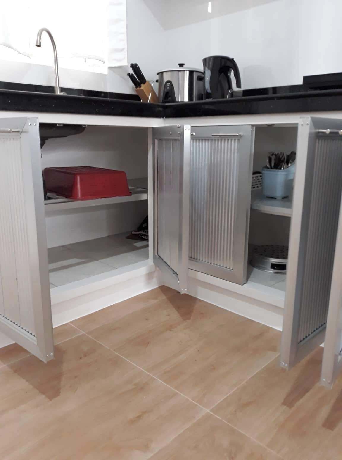 Una cocina con encimera negra, armarios de acero inoxidable y un contenedor rojo.