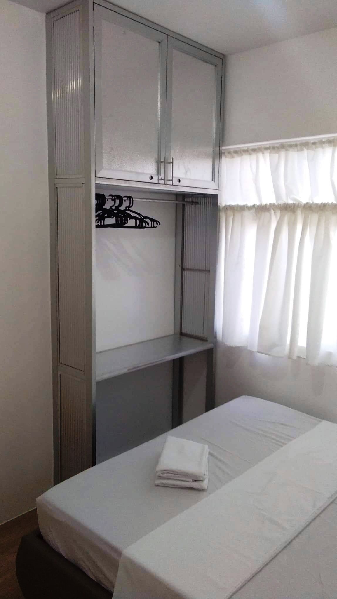 Una habitación de hotel con cama, armario y ventana con cortinas.