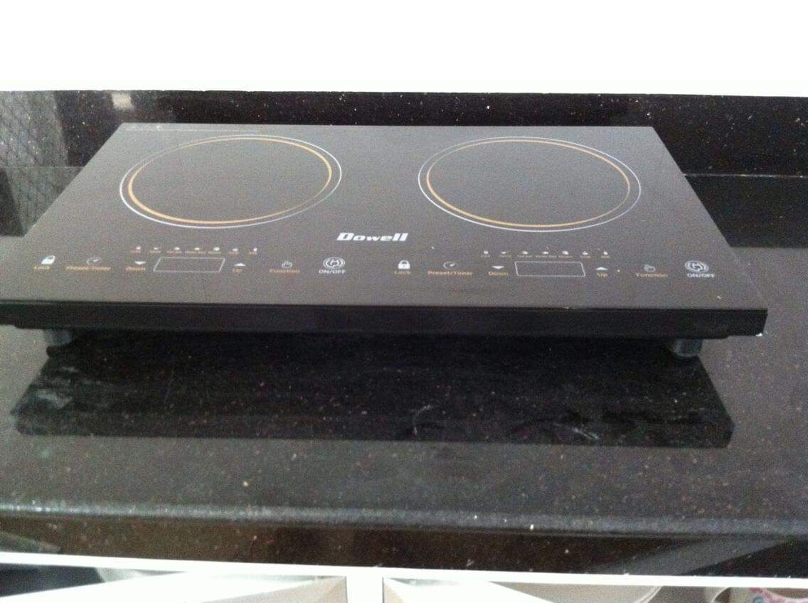 A black induction cooktop with two circular heating elements and a control panel with various buttons and indicators.