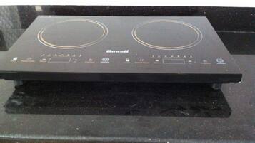 A black induction cooktop with two circular heating elements and a control panel with various buttons and indicators.