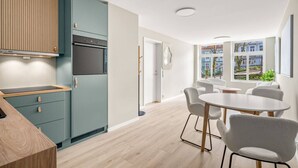 A modern kitchen with a dining area, featuring a wooden countertop, a built-in oven, and a dining table with chairs. - Dream Apartment – Central Living at Its Best! (Bergen)