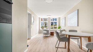 A modern, well-lit room with a dining area, a large window offering a view of the city, and a minimalist design. - Dream Apartment – Central Living at Its Best! (Bergen)