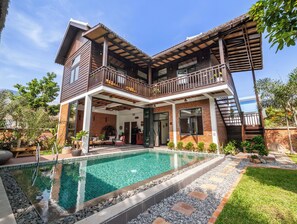 Ein zweistöckiges Haus mit Swimmingpool, Balkon und Garten.