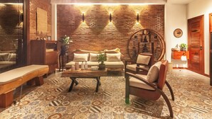 A cozy living room with a brick wall, a sofa, a coffee table, and patterned floor tiles. - 3BR Boutique Villa, Private Pool (Krong Siem Reap)