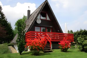 A house with a red staircase, a satellite dish, and a garden with red flowers.