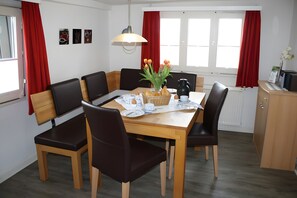 A dining area with a wooden table, black and brown chairs, a vase of tulips, and a kettle. - Apartment "Zum Torfstecher" in a quiet, central location with mountain views (Monschau)