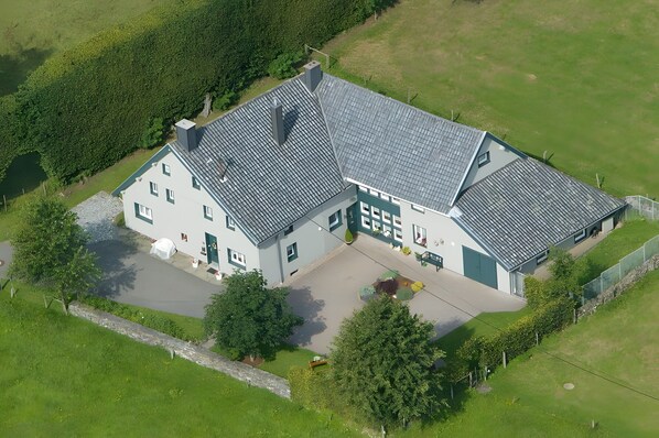 An aerial view of a large, two-story house with a sloped roof, a driveway, and a well-maintained lawn. - Apartment "Zum Torfstecher" in a quiet, central location with mountain views (Monschau)