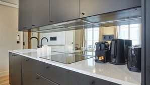 Eine moderne Küche mit einer großen Kochinsel, eingebauten Geräten und Blick zum Wohnbereich.