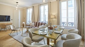 Ein modernes Wohnzimmer mit Essbereich, großen Fenstern und einem Fernseher.