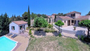 Una villa con piscina, una piccola dependance e un giardino con alberi e siepi.
