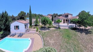 Una proprietà residenziale con piscina, una piccola casa indipendente e un edificio principale con tetto in tegole.