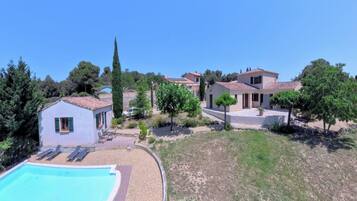 A residential property with a swimming pool, a small detached house, and a main house with a tiled roof.