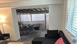 Et moderne interiør med en sort sofa, et træbord og et spiseområde i baggrunden.