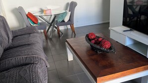 Ett modernt vardagsrum med en grå soffa, ett soffbord i trä och ett TV-bord.