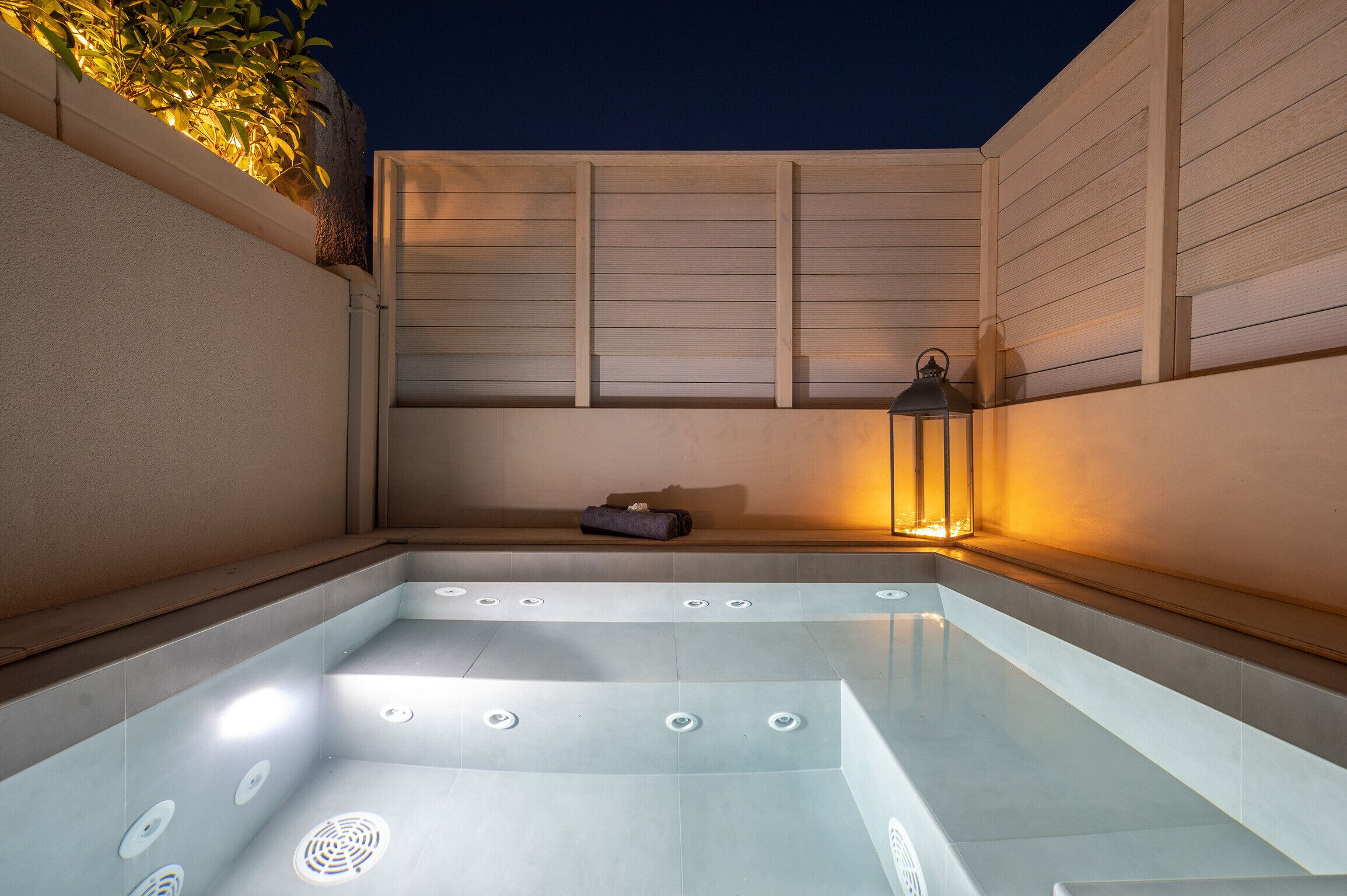 Un espace de détente avec un jacuzzi, un banc et une lanterne.