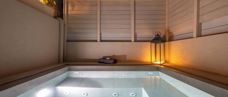 Un espace de détente avec un jacuzzi, un banc et une lanterne.