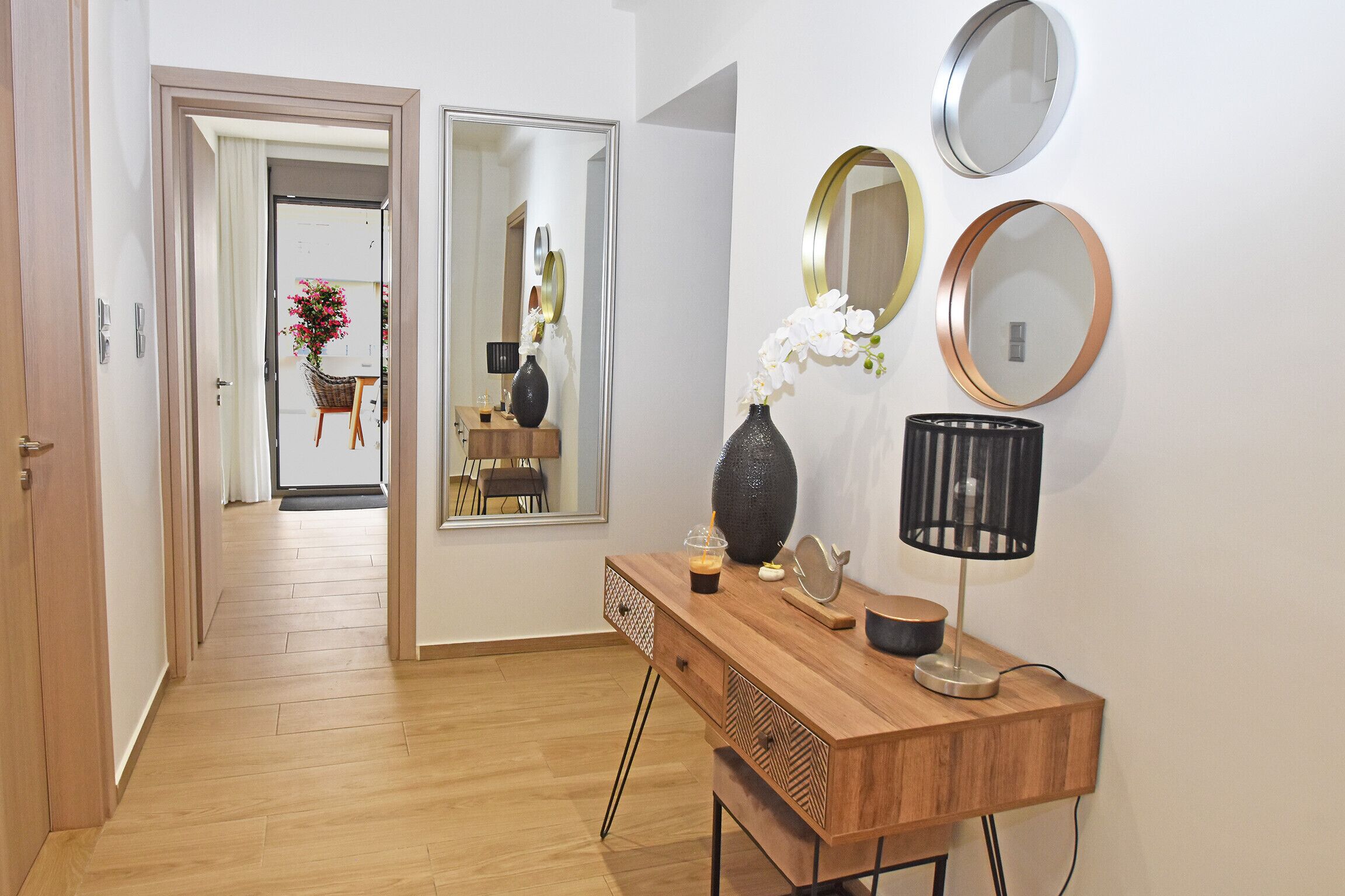 A wooden desk with a vase, a lamp, and a mirror.