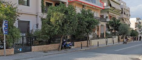 Un edificio de varios pisos con balcones, una acera empedrada y una calle.