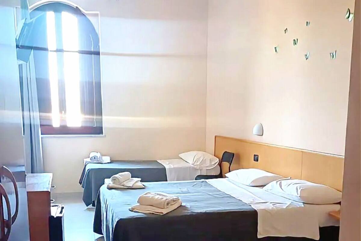 Une chambre d’hôtel avec deux lits, un bureau et une chaise.