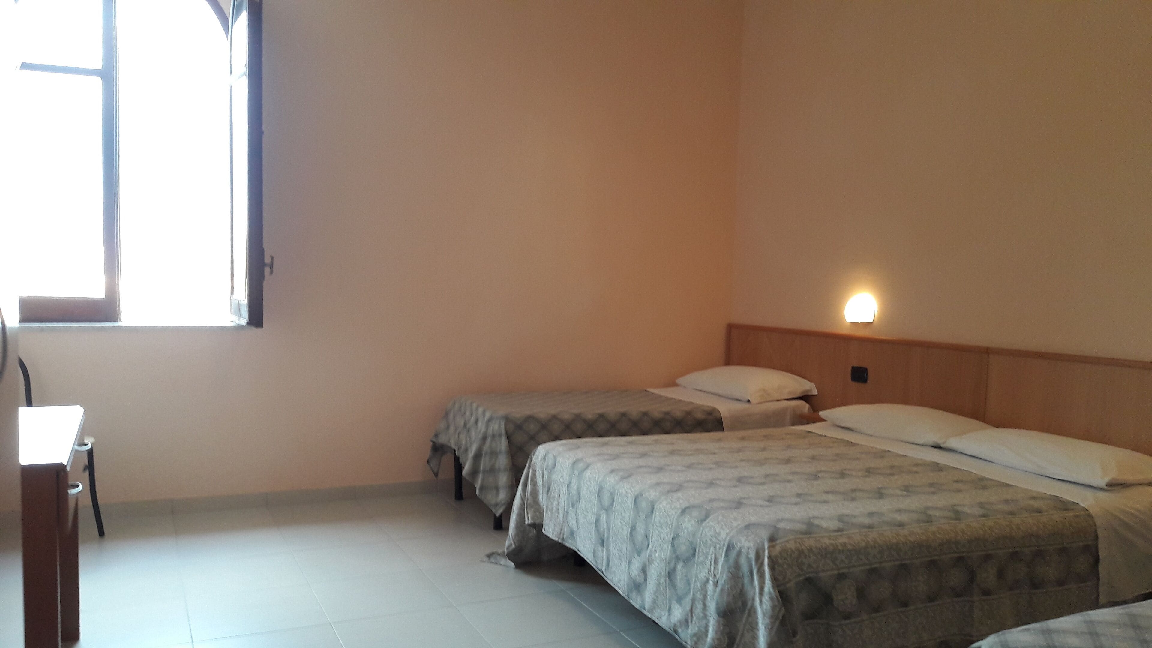 Habitación de hotel con dos camas, un escritorio y una ventana.