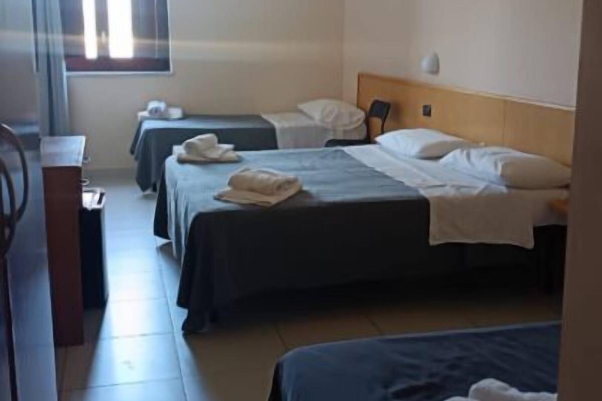 Une chambre d’hôtel avec deux lits simples, un bureau et une chaise.