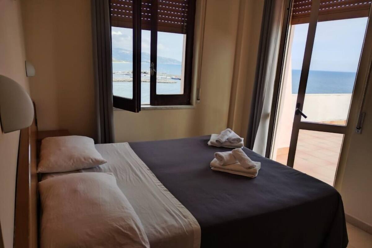 Une chambre d’hôtel avec un lit, deux oreillers, une couvre-lit sombre et une paire de serviettes.